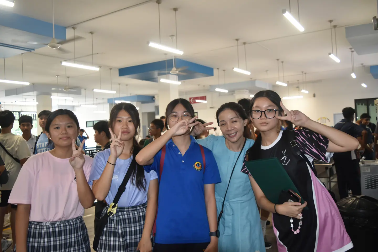 Students and a teacher posing together during a school reunion