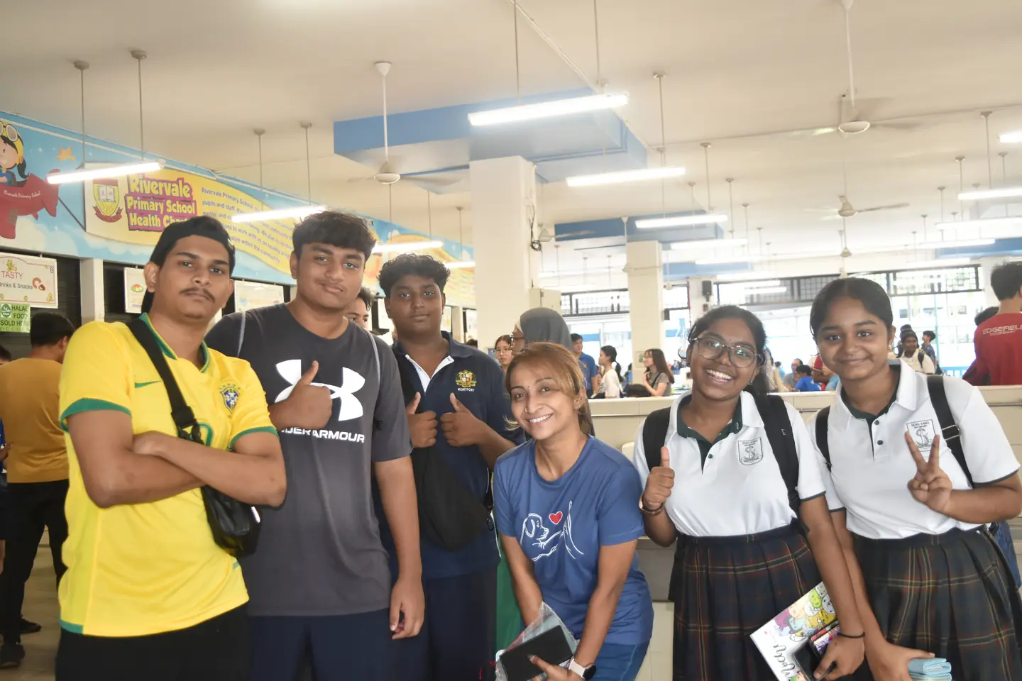 Graduates posing with a teacher in the school canteen